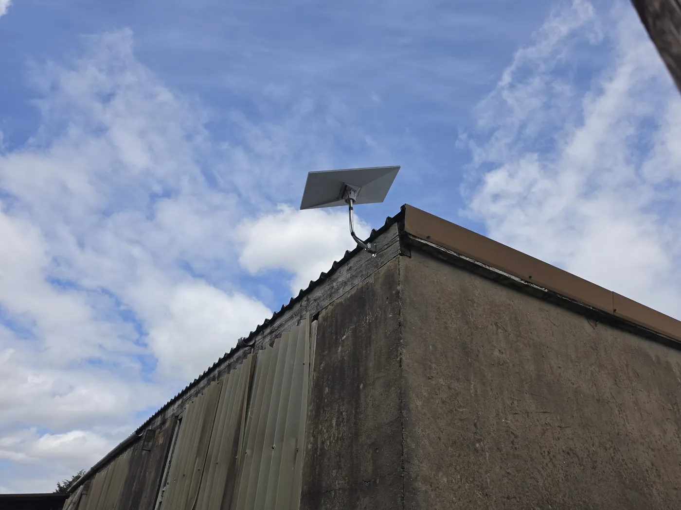 Starlink dish secured above a building roof edge with a clear view of the sky